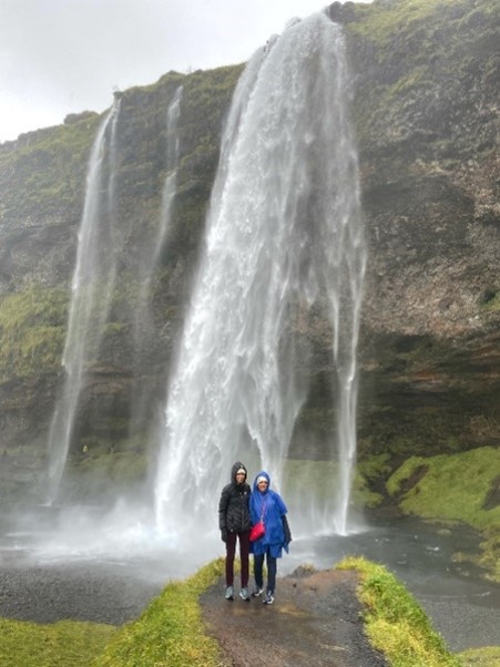 two people in raincoats standing in front of waterfalls 