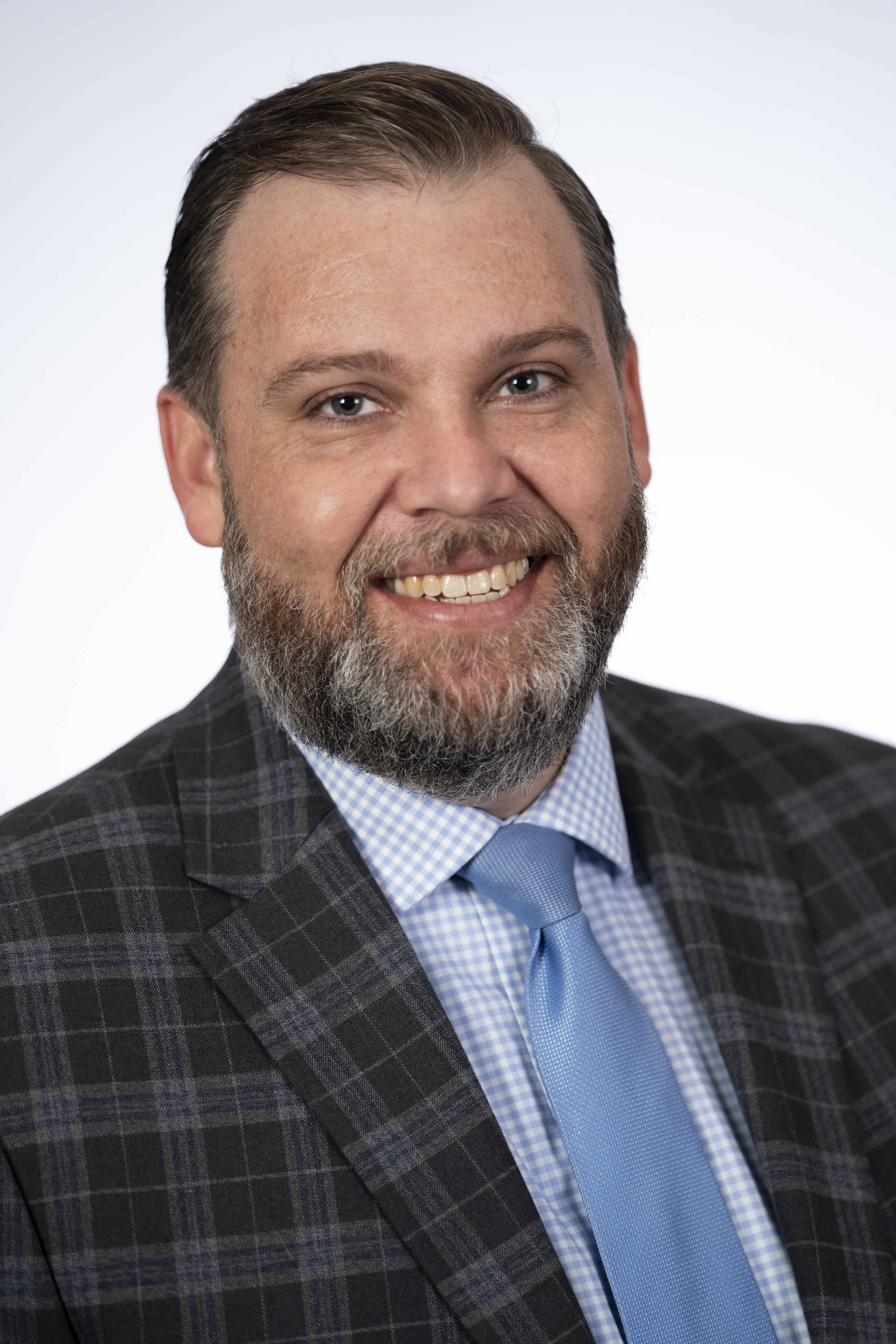 Man with beard in dark suit with blue tie